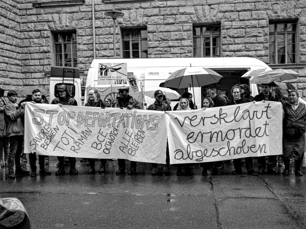 Foto von der Berlin Demonstration gegen die Abschiebung von Roma* nach Moldau. Personen halten Schilder und Transparente mit den Aufschriften „Versklavt Ermordet Abgeschoben“, „Stop Deportations“ und „Bleiberecht für alle – statt Chancenfalle“.